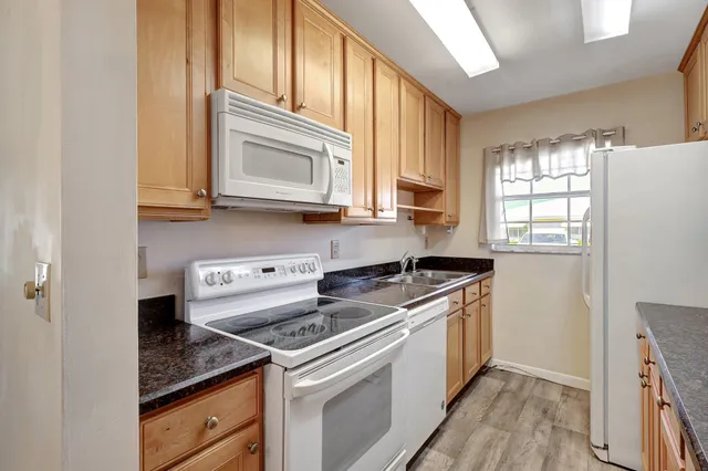a kitchen with granite countertop cabinets stainless steel appliances a sink and a window