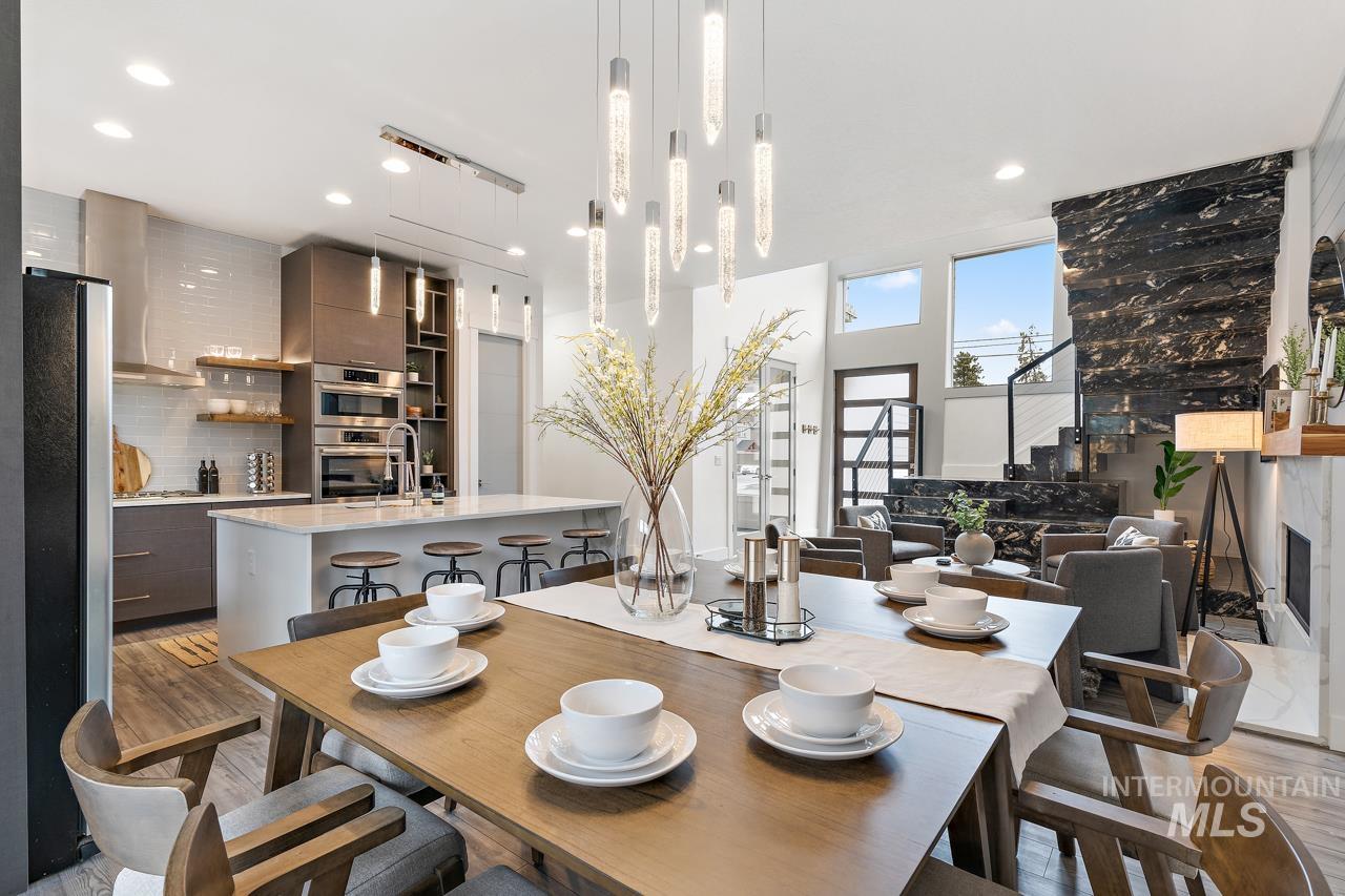 599 West Warren Street Boise, ID 83706 - Photo 11 of 41 Open-concept living space featuring a modern kitchen with an island, a dining area, a living area with a fireplace, a prominent dark stone feature wall, and a staircase with metal railings