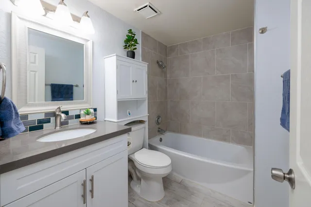 a bathroom with a granite countertop sink toilet a large mirror a bathtub and shower