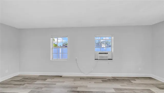 a view of an empty room with wooden floor and window