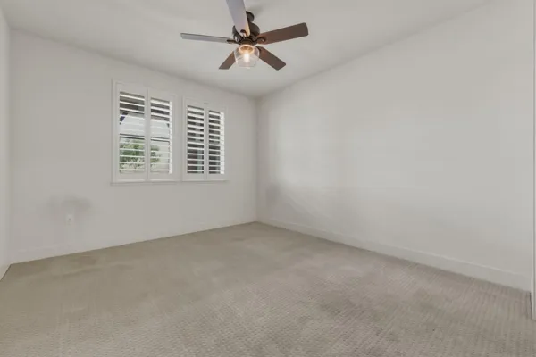 an empty room with a window and a fan