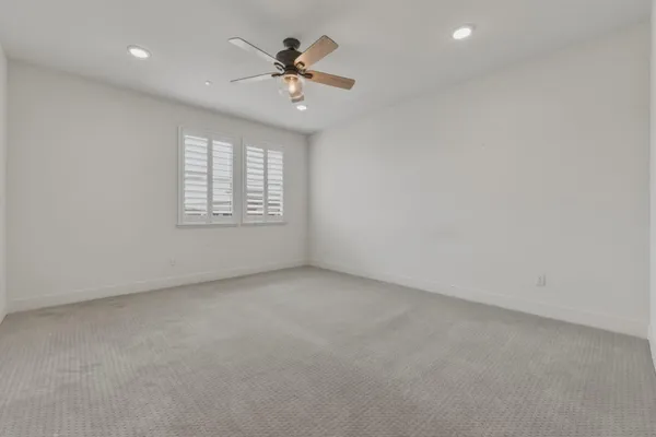 an empty room with a chandelier fan and windows