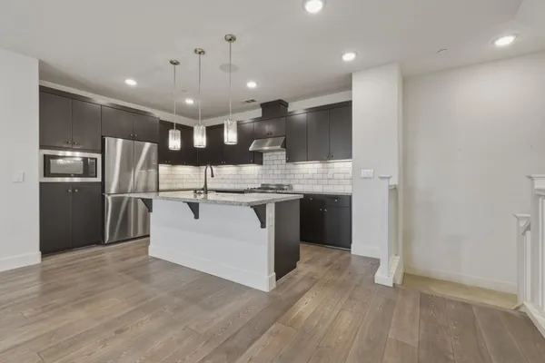 a kitchen with stainless steel appliances granite countertop a refrigerator a sink a stove and a microwave