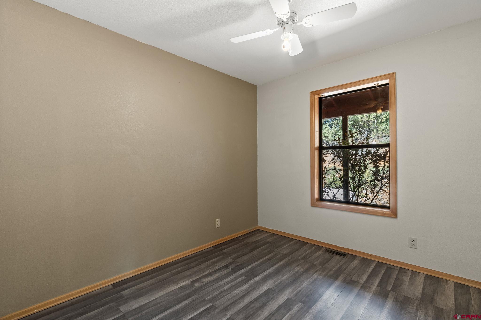 720 Sawmill Road Durango, CO 81303 - Photo 13 of 41 an empty room with wooden floor chandelier fan and windows