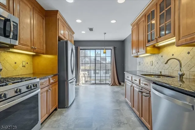 a kitchen with stainless steel appliances granite countertop a stove a sink and a refrigerator