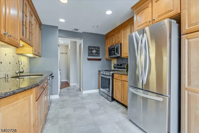 a kitchen with stainless steel appliances granite countertop a refrigerator a stove and a sink