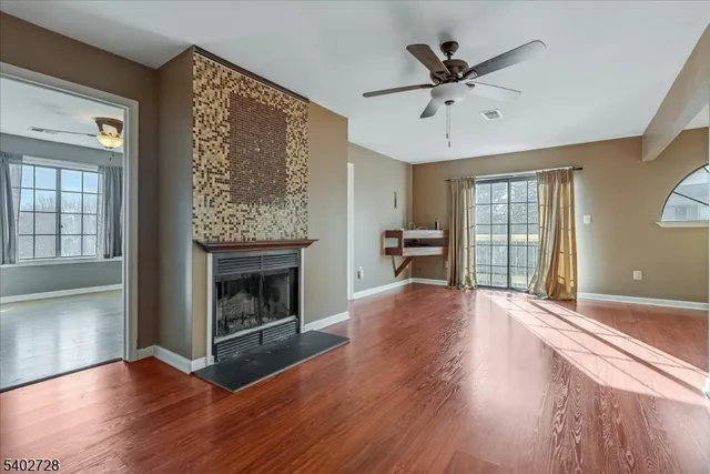 an empty room with wooden floor fireplace and windows
