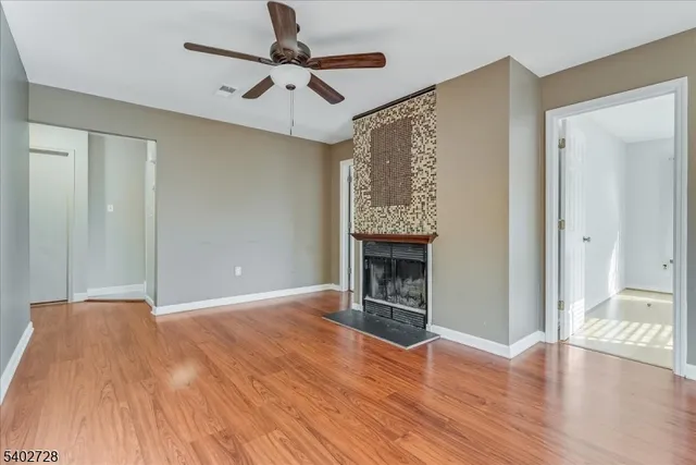 a view of an empty room with wooden floor fireplace and a window