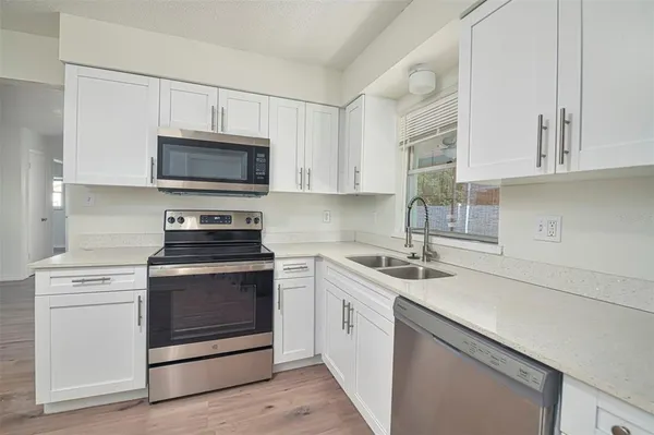 a kitchen with white cabinets stainless steel appliances and sink