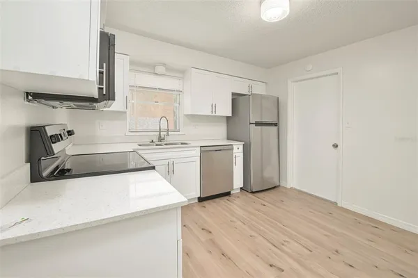 a kitchen with a sink a stove cabinets and wooden floor