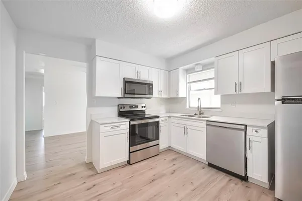 a kitchen with white cabinets stainless steel appliances and sink