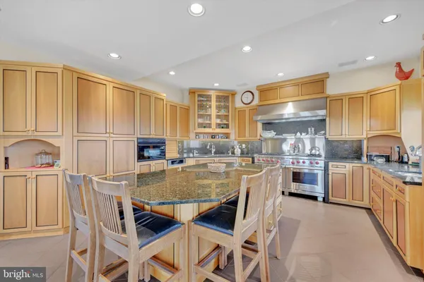 a kitchen with kitchen island granite countertop lots of white cabinets and stainless steel appliances