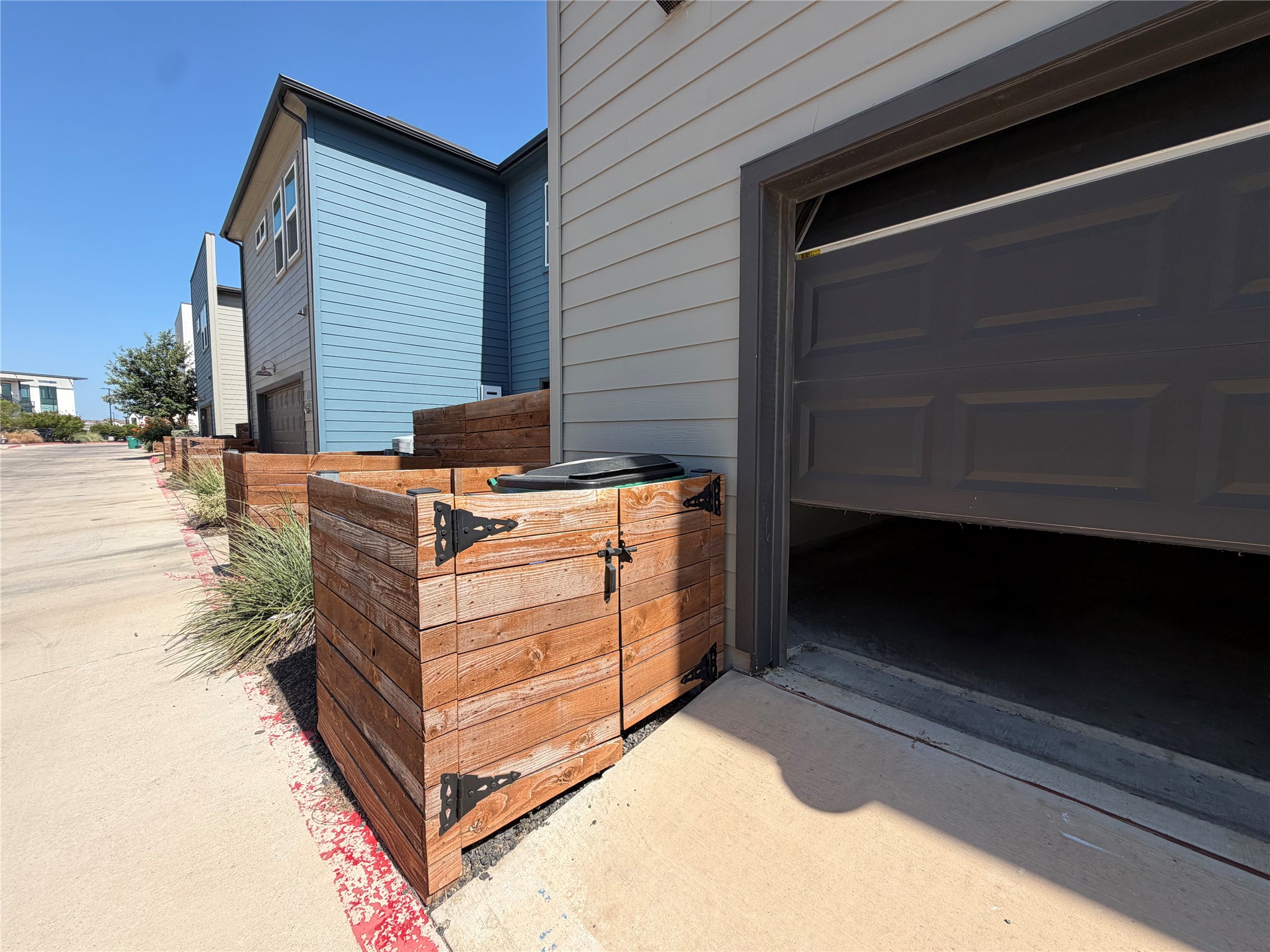 9015 Cattle Baron Path, Unit 605 Austin, TX 78747 - Photo 24 of 29 An open garage reveals concrete flooring alongside custom wood fencing and clean siding.
