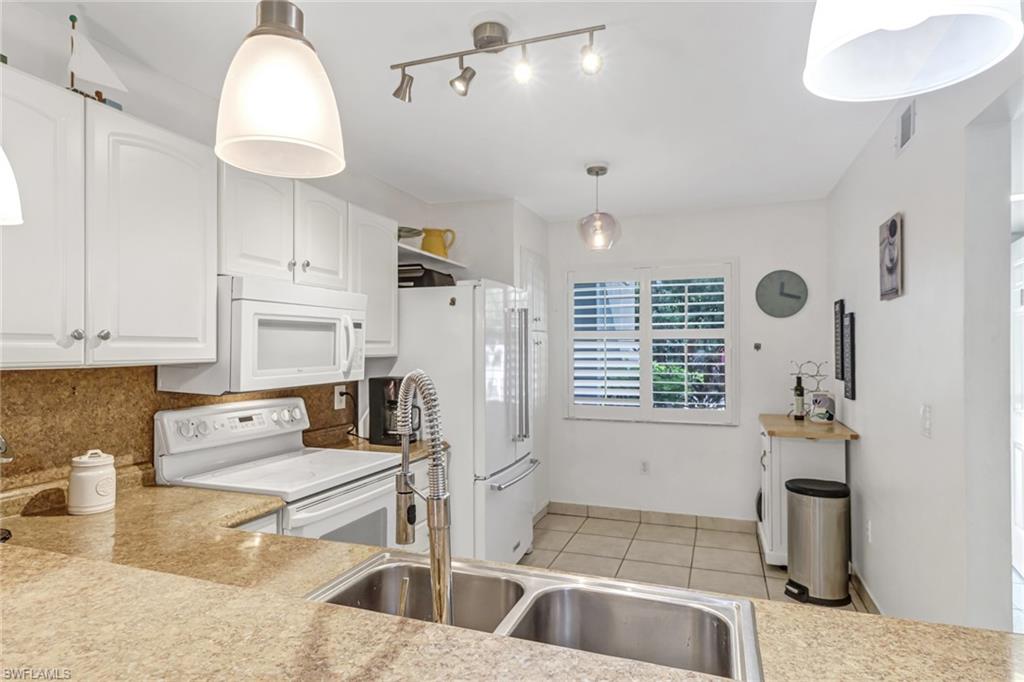 5675 Whitaker Road, Unit B101 Naples, FL 34112 - Photo 13 of 45 a kitchen with granite countertop a sink a counter and a stove