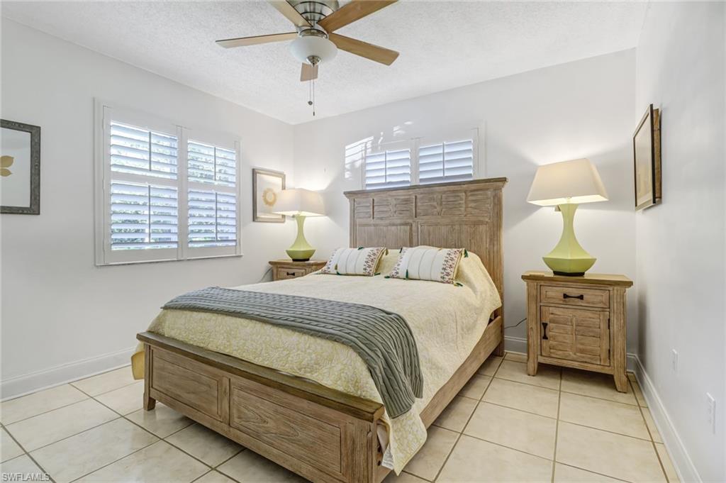 5675 Whitaker Road, Unit B101 Naples, FL 34112 - Photo 17 of 45 a bedroom with a bed and a chandelier