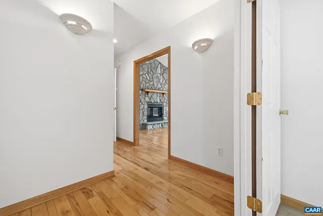 a view of a hallway with wooden floor and a bathroom