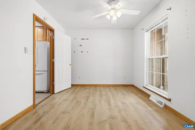 an empty room with wooden floor closet and windows