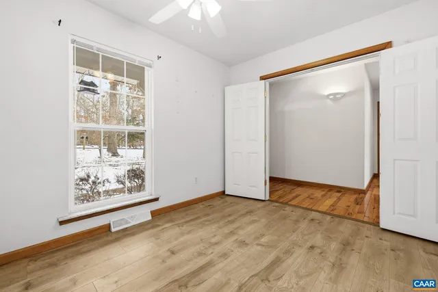 an empty room with wooden floor and windows