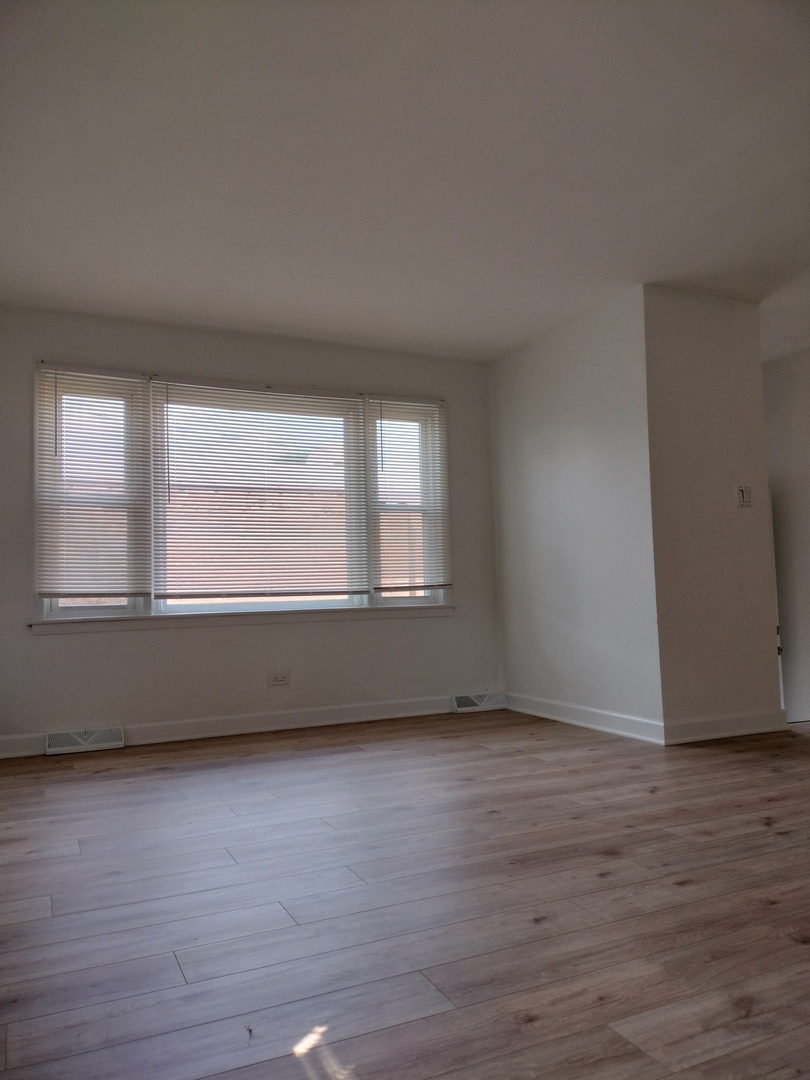 7910 South Muskegon Avenue, Unit 3 Chicago, IL 60617 - Photo 3 of 17 a view of an empty room with wooden floor and a window
