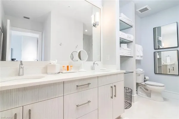 a bathroom with double sink a toilet and a mirror