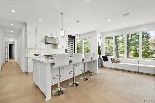 a large white kitchen with lots of counter space a sink appliances and a large window