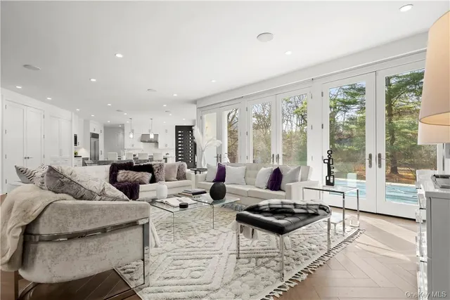 a living room with furniture large windows and wooden floor