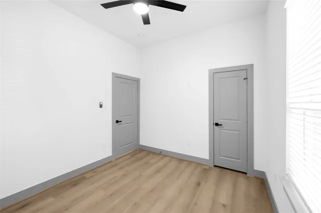 an empty room with a hardwood and ceiling fan