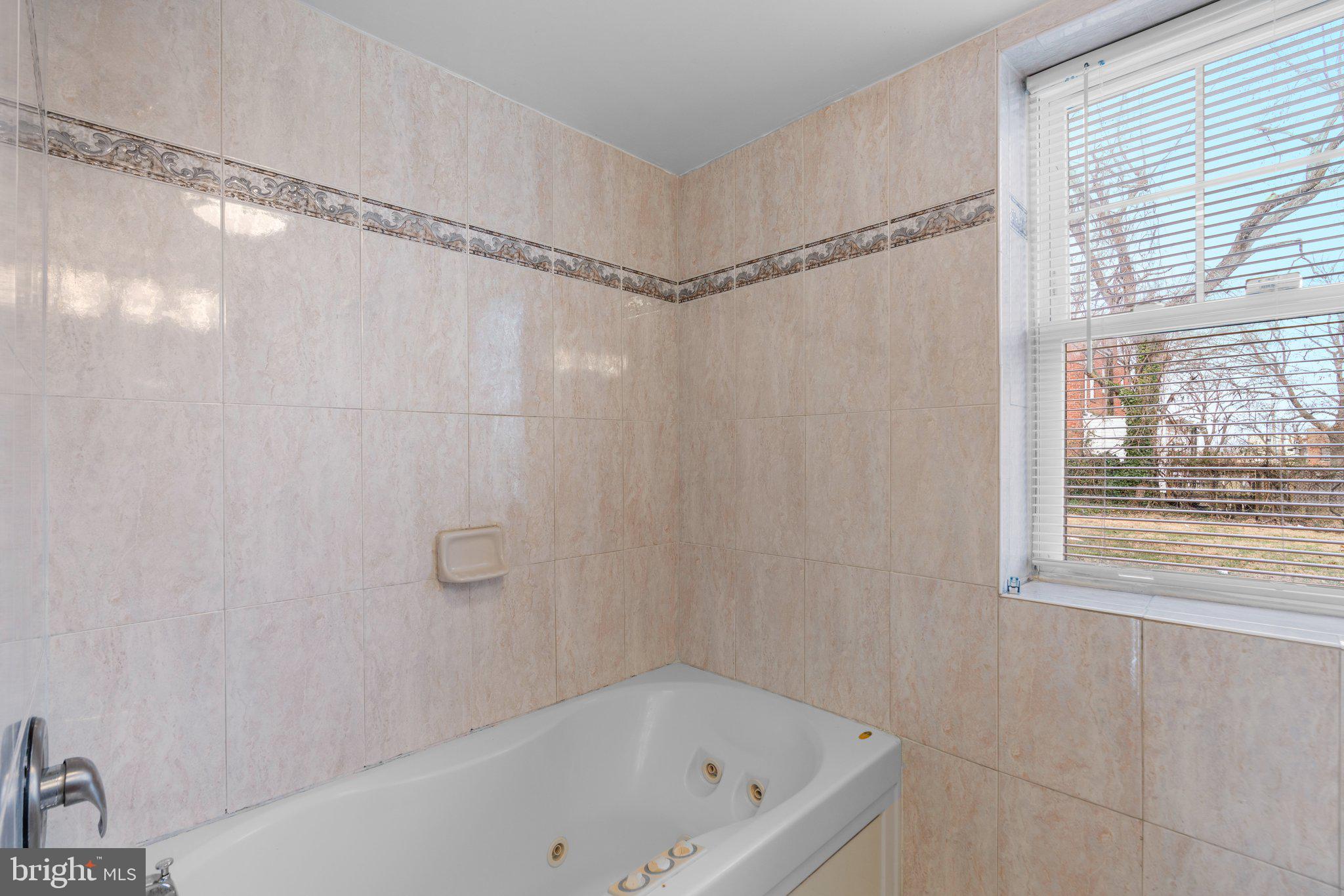 3866 9th Street Southeast, Unit 101 Washington, DC 20032 - Photo 18 of 24 a bathroom with a bathtub and a shower