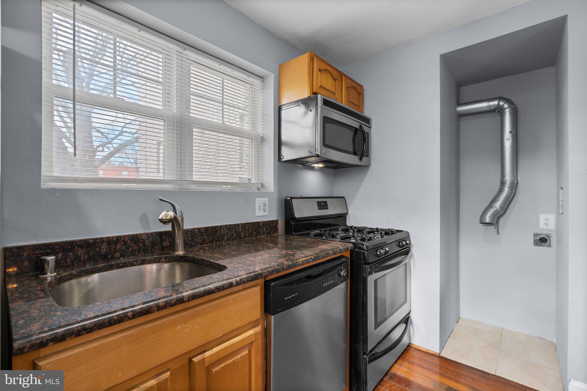 3866 9th Street Southeast, Unit 101 Washington, DC 20032 - Photo 10 of 24 a kitchen with stainless steel appliances granite countertop a sink stove and microwave