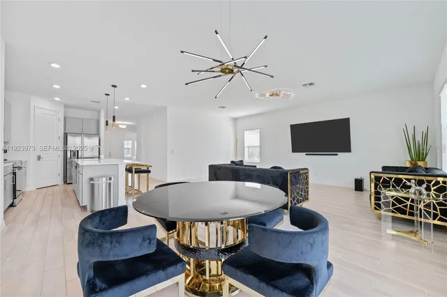 a living room with furniture a flat screen tv and kitchen view