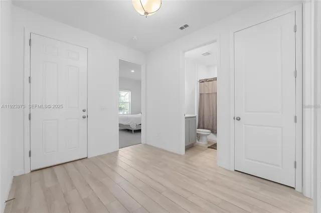 a view of a hallway with wooden floor and a bathroom