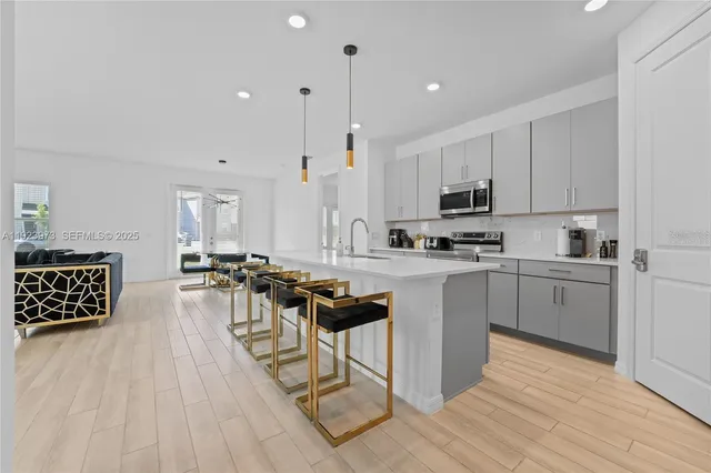 a kitchen with stainless steel appliances a stove a sink a oven a dining table and chairs