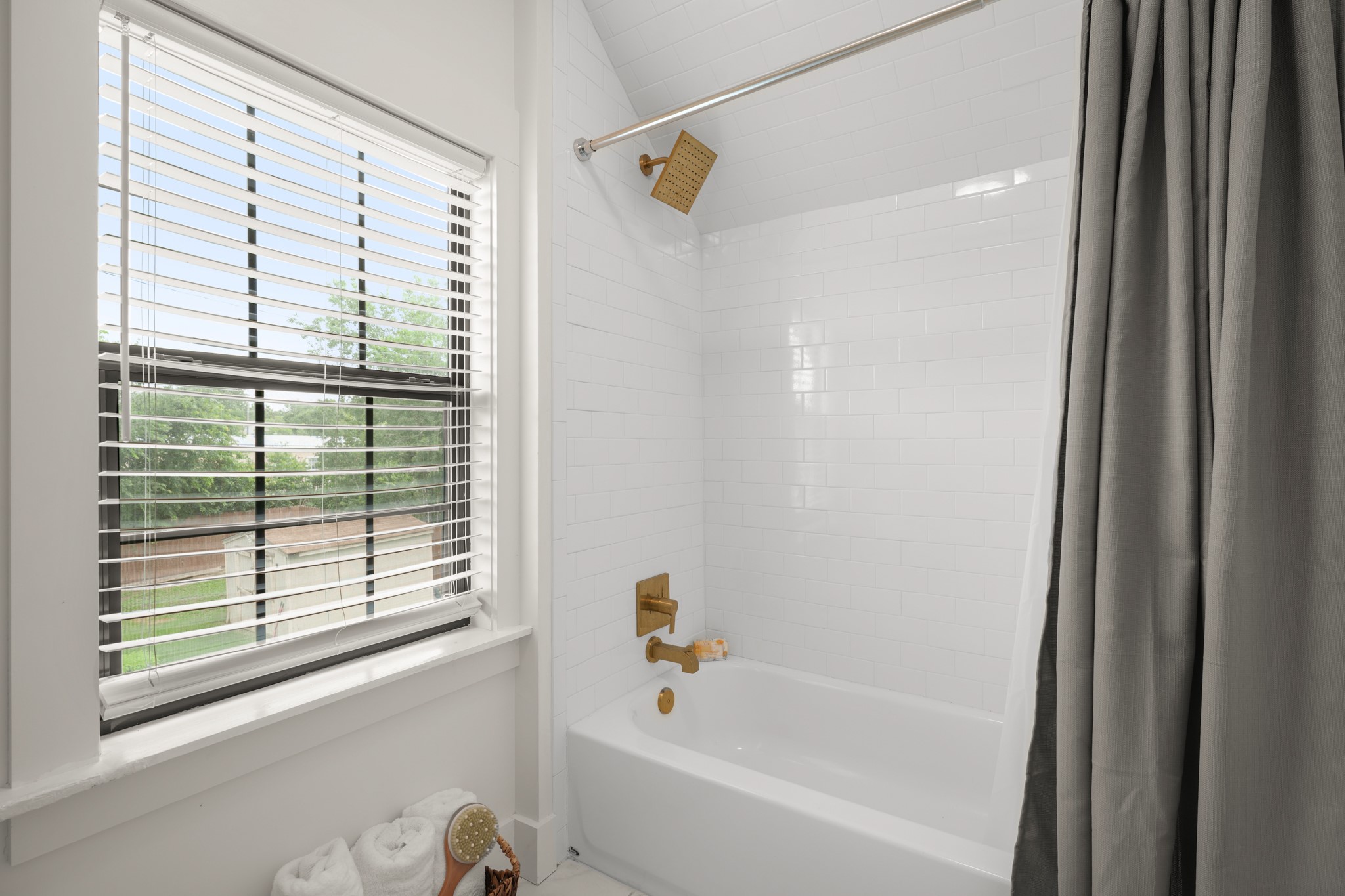 301 Old Thorndale Road Taylor, TX 76574 - Photo 23 of 29 A well-appointed bathroom features a full-sized tub and shower with gold-toned fixtures and classic subway tile.