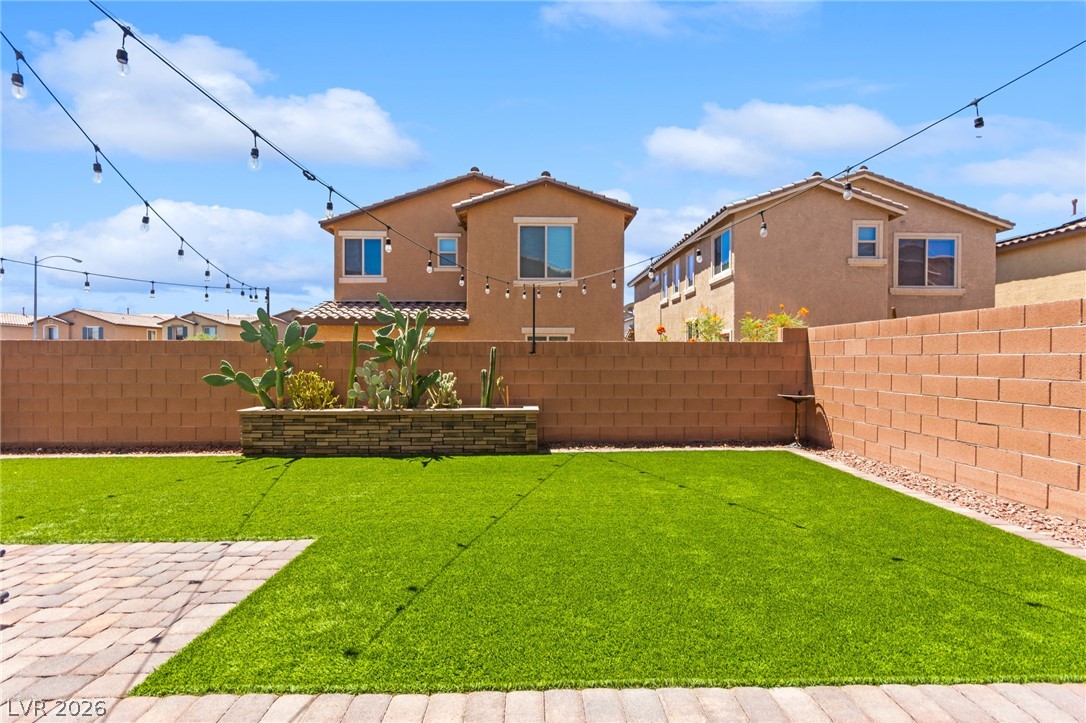 6435 Point Isabel Way Las Vegas, NV 89122 - Photo 42 of 57 A low-maintenance backyard boasts artificial turf and charming string lighting for evening ambiance.