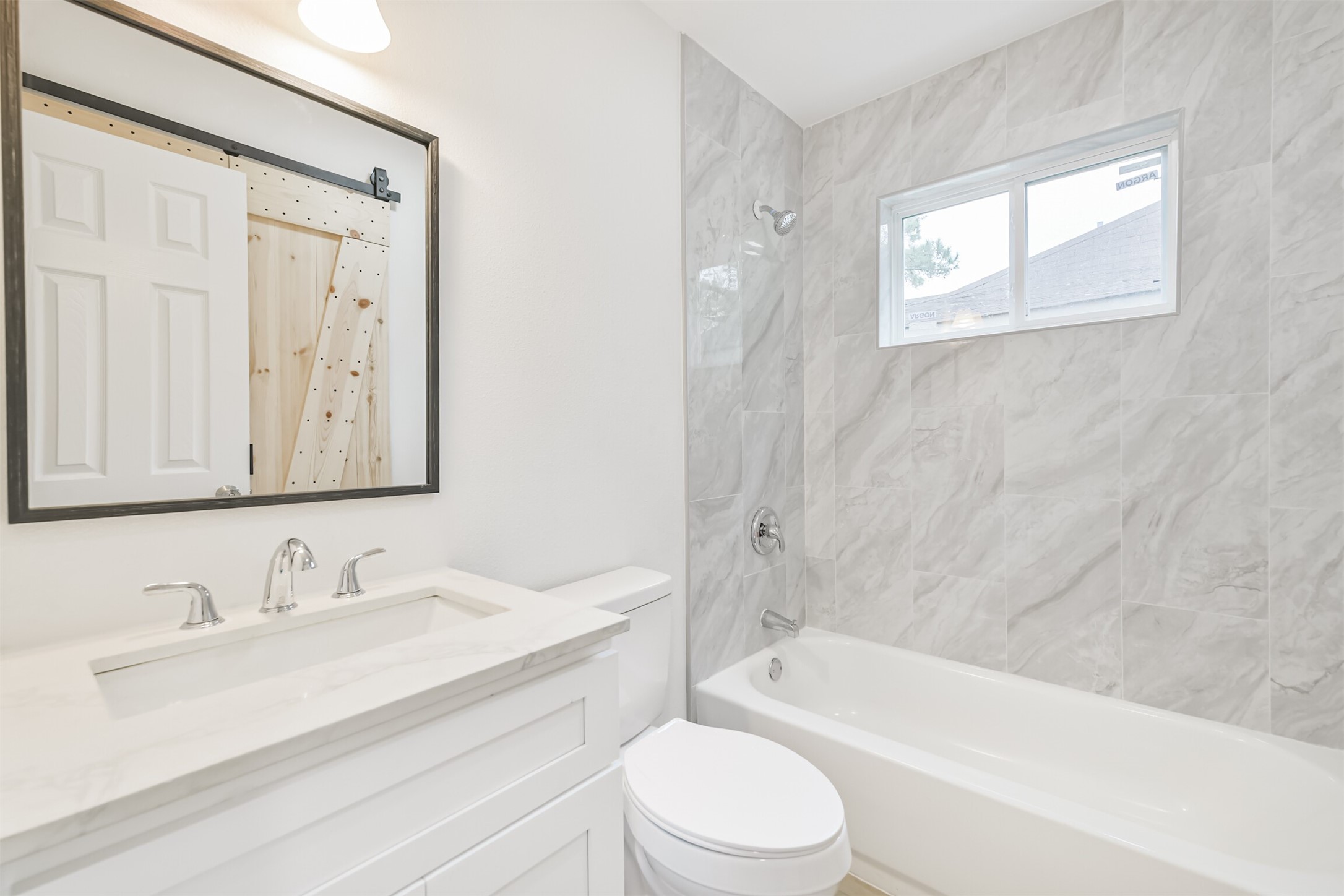 4215 Rosegate Drive Spring, TX 77373 - Photo 28 of 38 The guest bathroom features a tub/shower combo with ceiling high tile surround. The enlarged closet behind the entrance is easily accessible with the custom-built bi-fold barn doors.