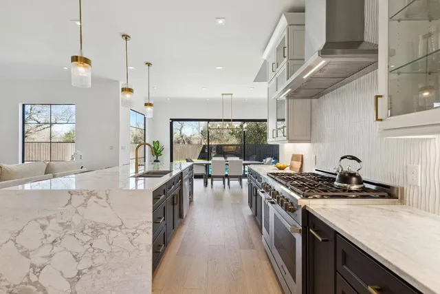 a kitchen with stainless steel appliances granite countertop a stove a sink dishwasher a dining table and chairs with wooden floor