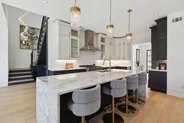 a kitchen with stainless steel appliances granite countertop a sink a stove and a wooden floor