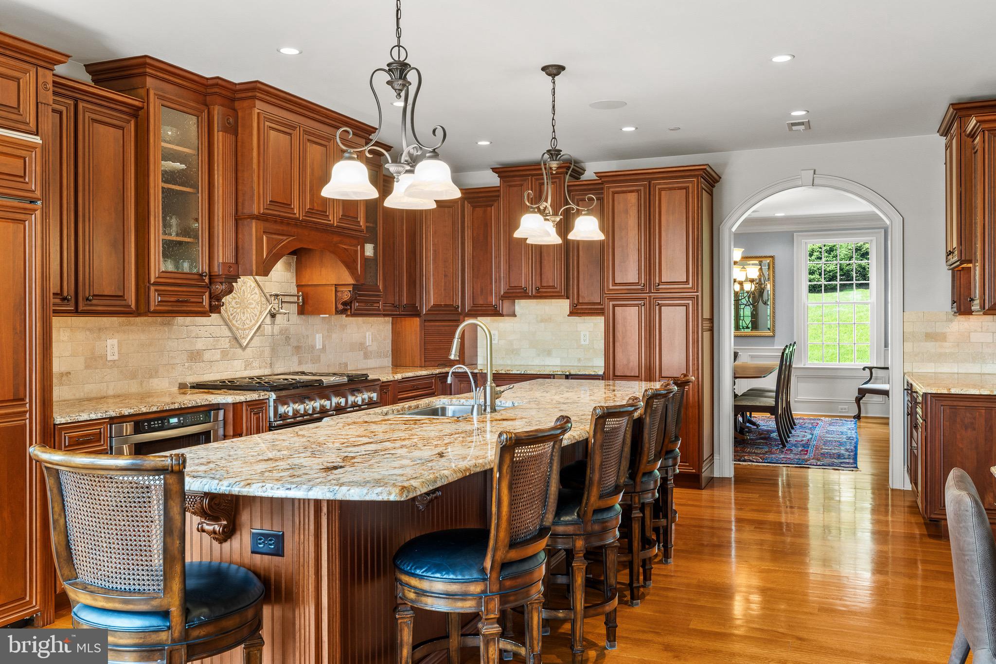 5835 Ridgeview Drive Doylestown, PA 18902 - Photo 24 of 63 a kitchen with stainless steel appliances granite countertop a stove top oven a dining table and chairs with wooden floor