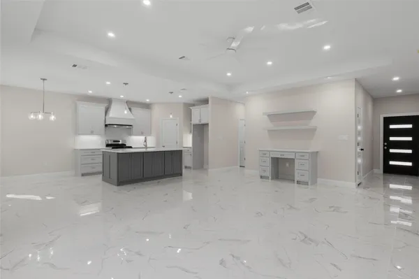 a large white kitchen with kitchen island a sink stainless steel appliances and cabinets