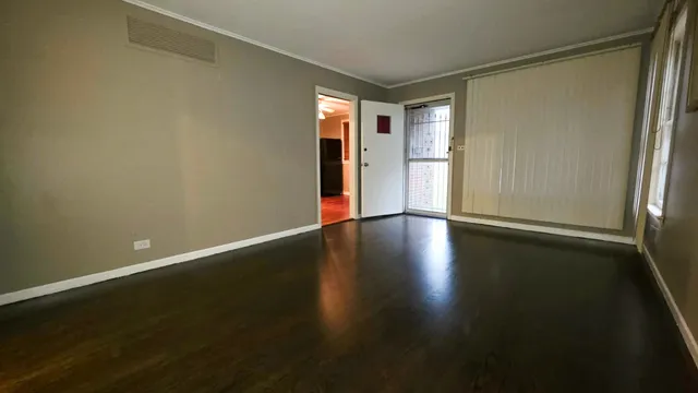 an empty room with wooden floor and windows with curtains