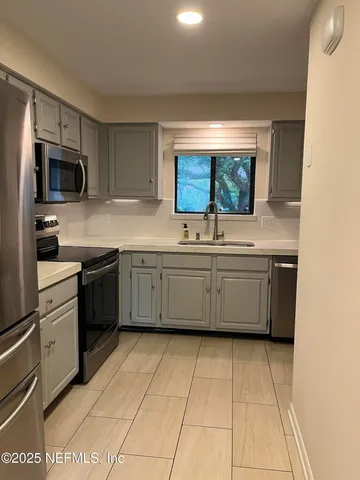 a kitchen with stainless steel appliances a sink counter top space cabinets and a window