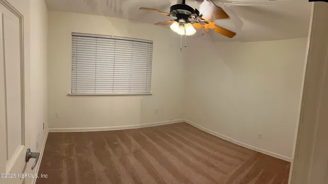 an empty room with a window and a fan