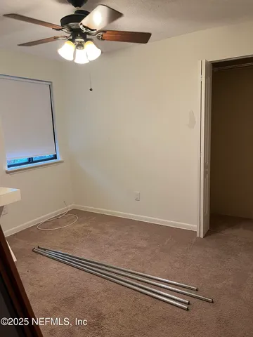 a view of a room with wooden floor and a ceiling fan