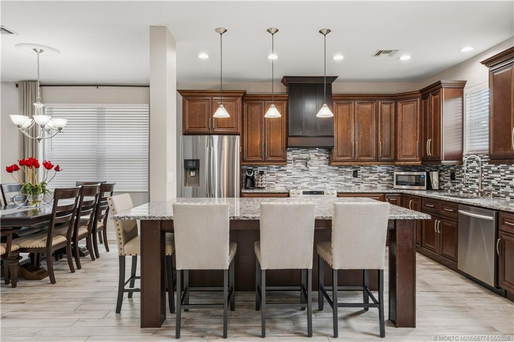 1268 Southeast Kirk Street Stuart, FL 34997 - Photo 23 of 63 a kitchen with stainless steel appliances kitchen island granite countertop a dining table chairs sink and cabinets