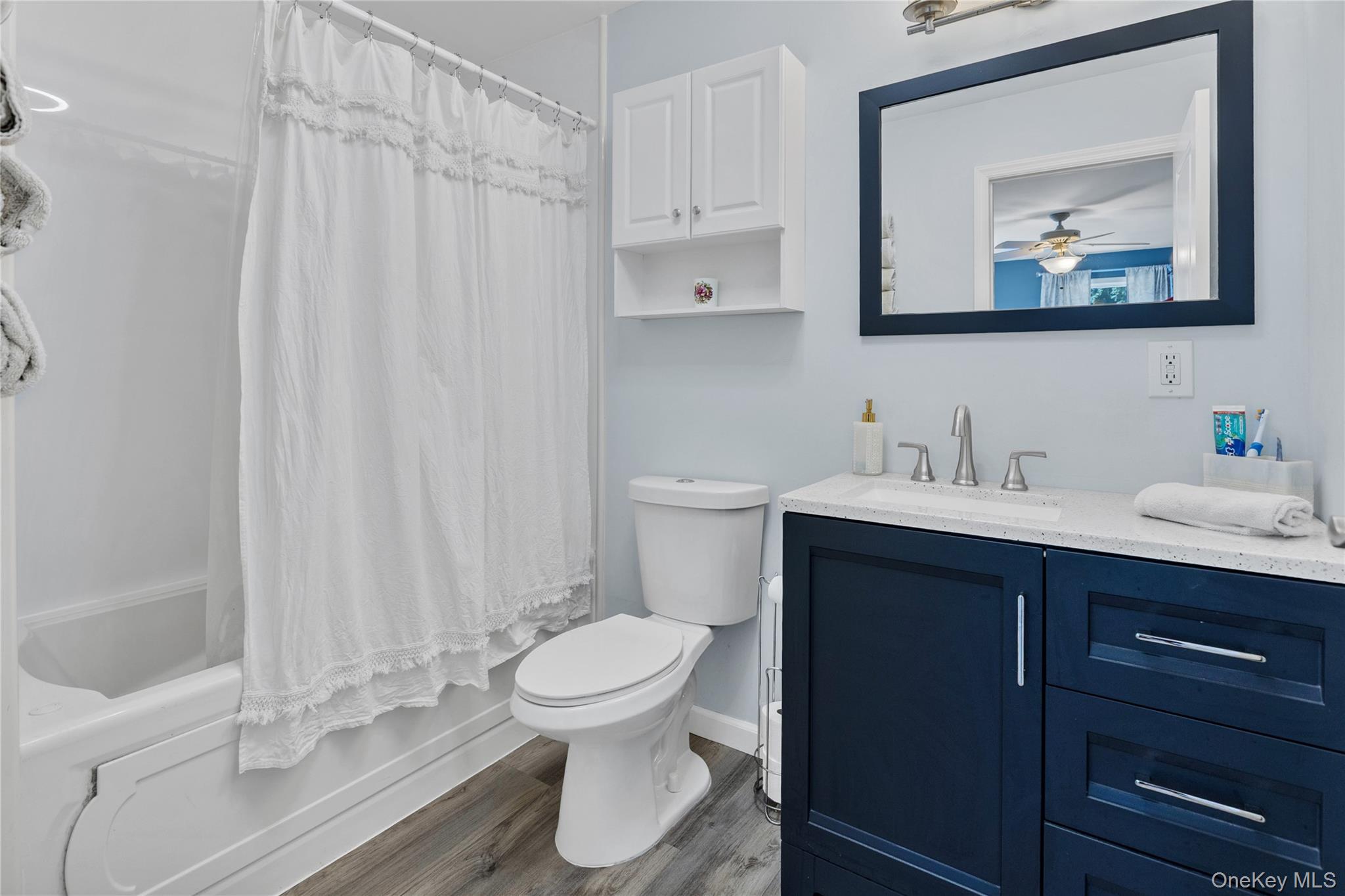 6 Giant Oak Road Ridge, NY 11961 - Photo 15 of 22 Bathroom featuring a dark blue vanity with a light-colored countertop, an undermount sink, and a framed mirror