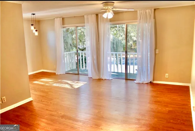 a view of empty room with wooden floor and fan