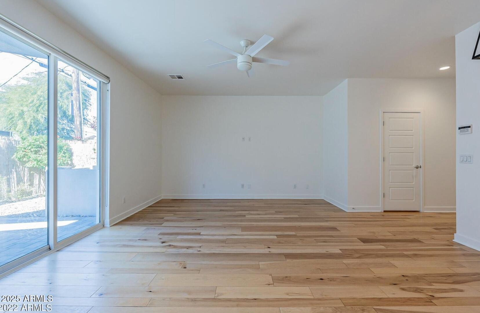 3030 North 38th Street, Unit 113 Phoenix, AZ 85018 - Photo 9 of 22 a view of an empty room with wooden floor and a window