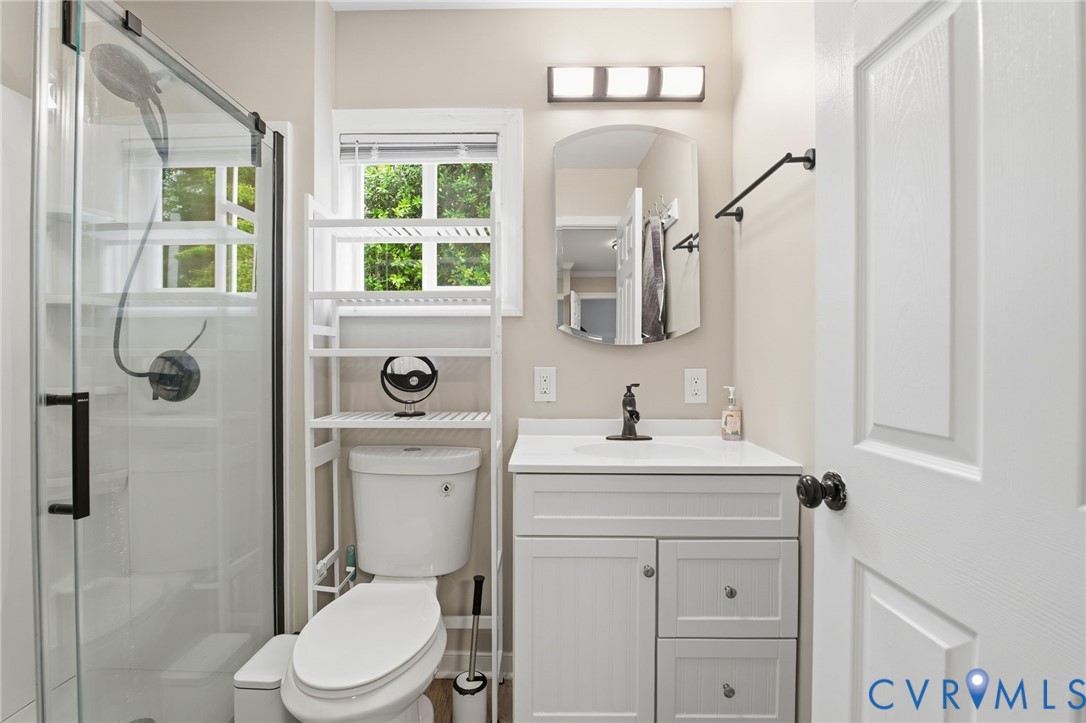 9110 Gayton Road Henrico, VA 23229 - Photo 19 of 54 a bathroom with a toilet a sink a mirror a window and vanity