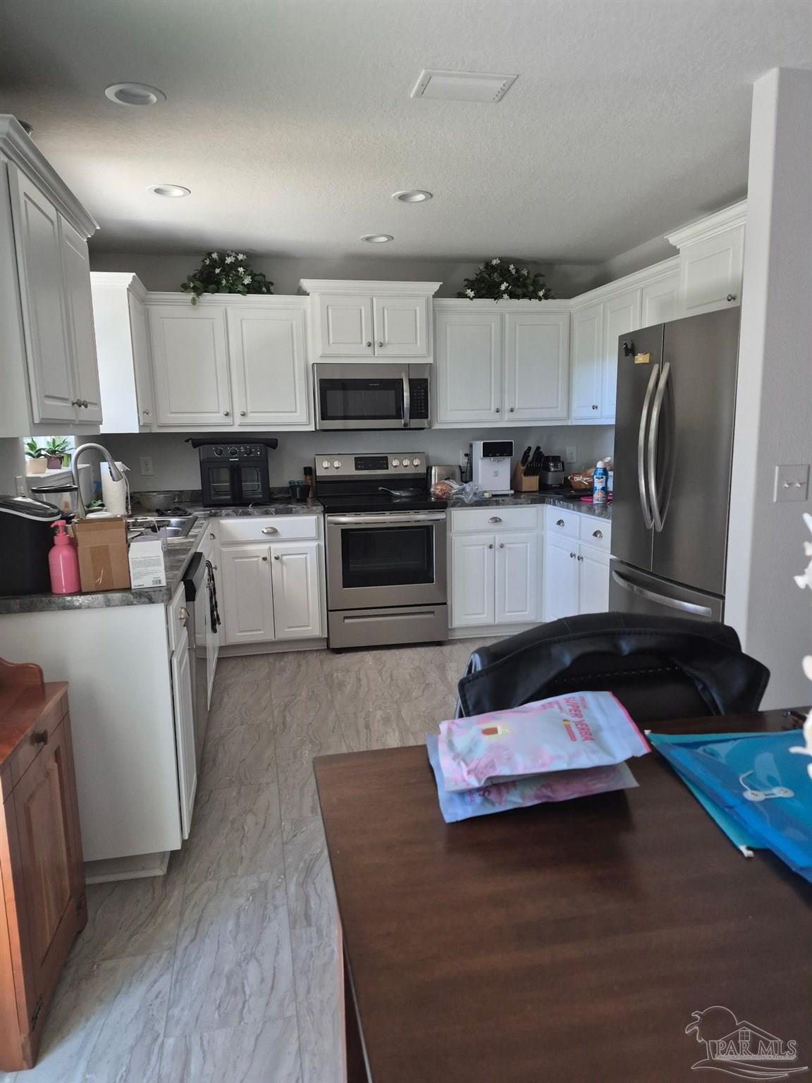 5538 Holley Street Milton, FL 32583 - Photo 3 of 6 a kitchen with kitchen island granite countertop a sink cabinets and stainless steel appliances