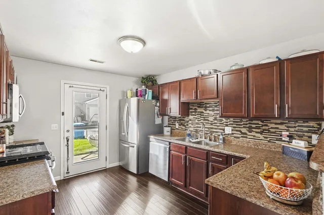 a kitchen with stainless steel appliances granite countertop a refrigerator and a stove top oven
